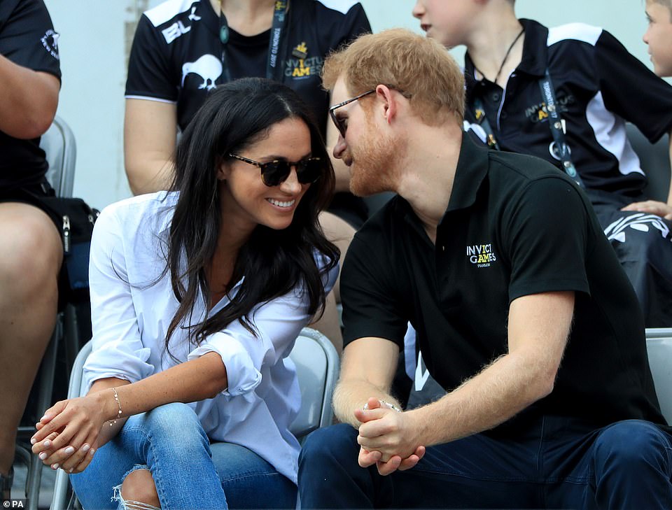 What a loved-up pair! Prince Harry eschewed royal formality as he affectionately kissed Meghan on the head while holding hands as they made their way to their seat at the wheelchair tennis during today's Invictus Games in Toronto