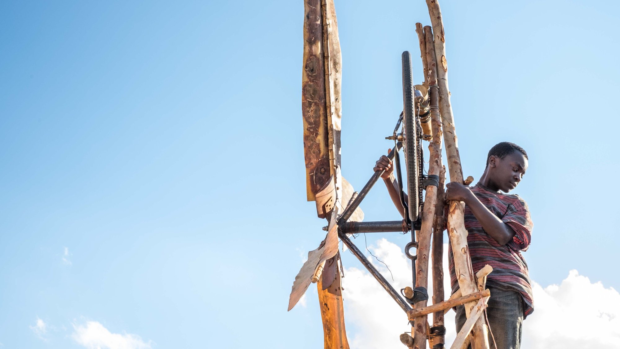 A Black boy looks down from his invention in "The Boy Who Harnessed the Wind"