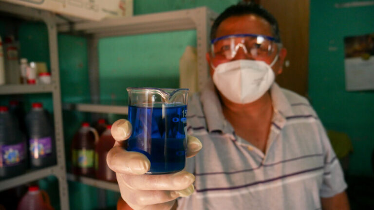 Former Salvadoran guerrilla David Henríquez, deported from the United States in 2019, shows the quality of the disinfectant he has just produced in his small artisanal workshop in San Salvador. With no chance of finding formal employment after deportation, he worked hard to set up his disinfectant business to generate an income. CREDIT: Edgardo Ayala/IPS