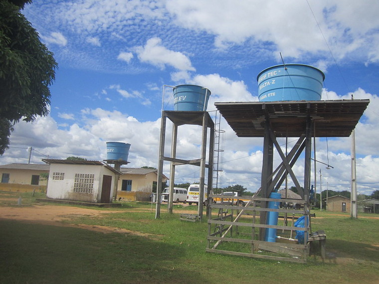 A photo of the three water tanks in the village of Darora, one of which holds water that is made potable by chemical treatment. The largest and longest building is the secondary school that serves the Macuxi indigenous community that lives in Roraima, in northern Brazil. CREDIT: Mario Osava/IPS