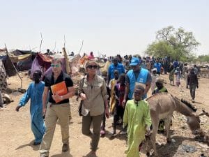 ECW’s Yasmine Sherif and Graham Lang walk with UNHCR partners through Borota, where thousands of new refugees, most of them women, and children, have arrived after fleeing the conflict in Sudan. Credit: ECW