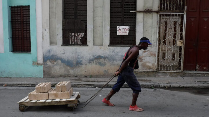 A man pulls a cart loaded with building blocks past a house for sale in the municipality of Centro Habana. In view of the government's diminished construction capacity and the decline of funds for housing, since 2010 the government authorized the free sale of various materials for construction, repairs, remodeling and expansion. CREDIT: Jorge Luis Baños / IPS
