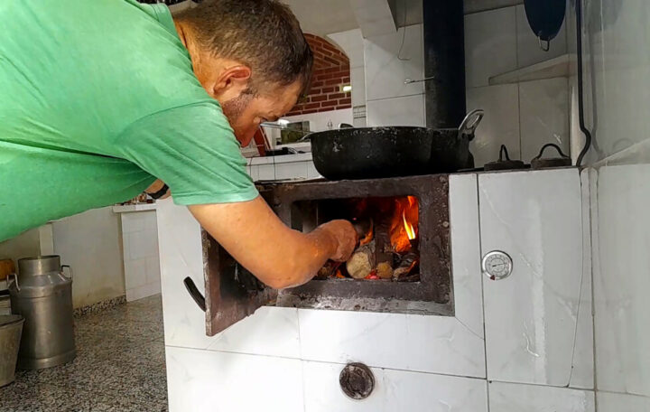 Lorenzo Díaz feeds firewood into an innovative stove that allows the Finca del Medio farm to efficiently cook food, dehydrate or dry fruits and spices, heat water and preserve meat, among other functions. CREDIT: Jorge Luis Baños / IPS