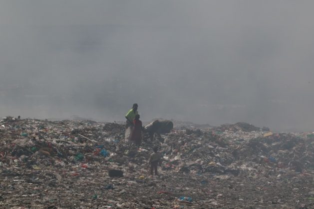 A mother and her children are seen wading through a cloud of smoke at the Dandora dumpsite, Kenya's largest open landfill. Smoke emanating from the dumpsite is cited as a contributor to air pollution in Nairobi. Credit: Jackson Okata/IPS