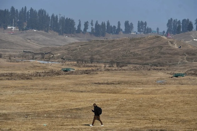 A man walks through an area in Kashmir where low snowfall is causing concern as the region’s economy is highly dependent on it. Credit: Umar Manzoor Shah/IPS