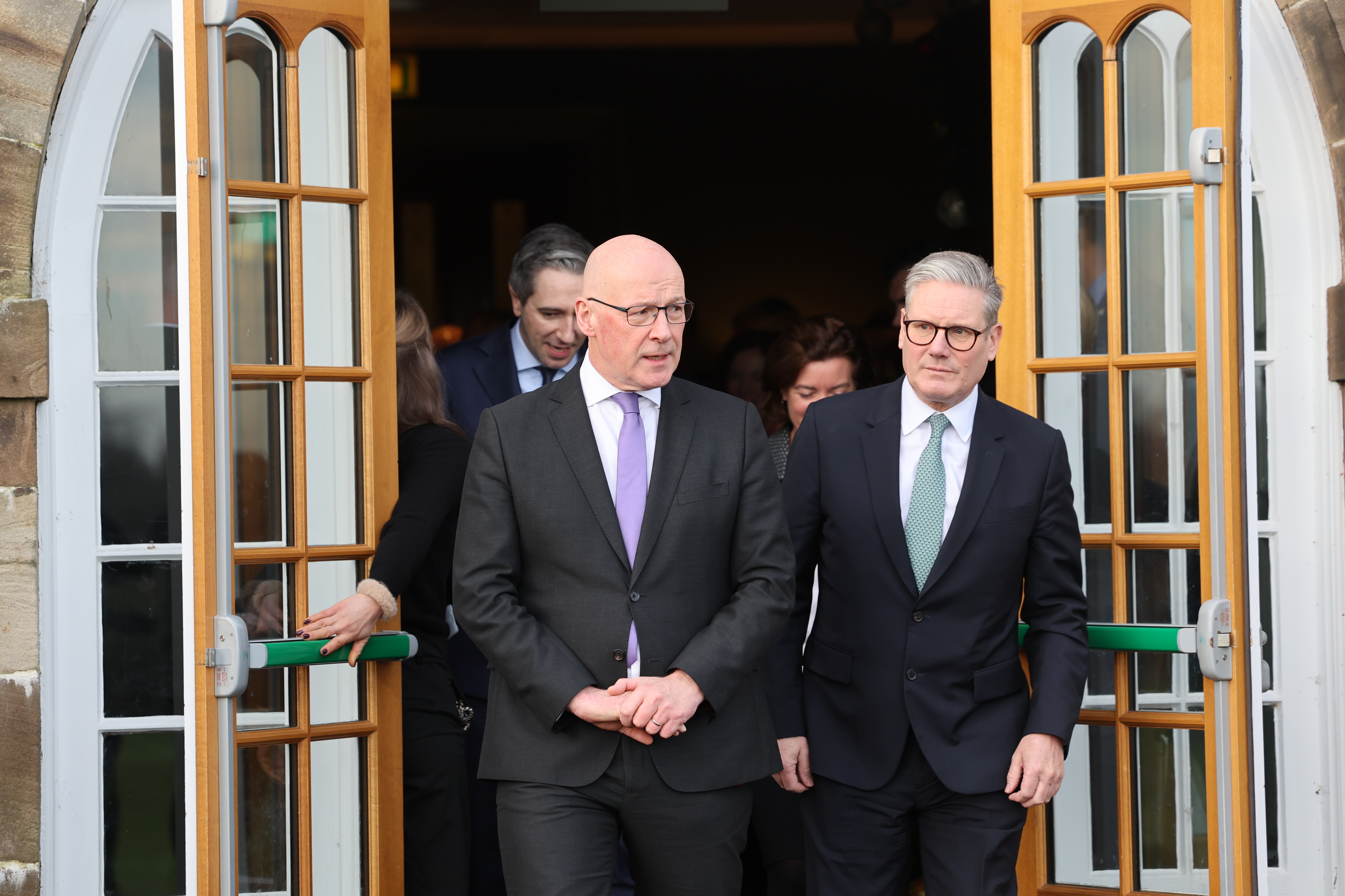 First Minister of Scotland John Swinney and British Prime Minister Sir Keir Starmer exiting a doorway.