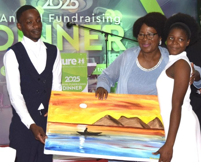 Ansah (centre) receives a portrait from beneficiaries of surgical operations Steven Muzolo (left) and Saraphina Thomson (002)