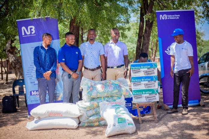 NBM Nchalo Service Centre Manger Watson Fulutuna (second left) handing over food stuff and perking braillers to Makande (002)